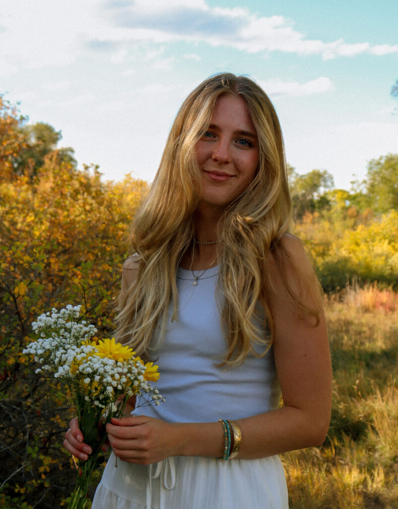 Headshot of Ashley holding flowers in an autumn field.