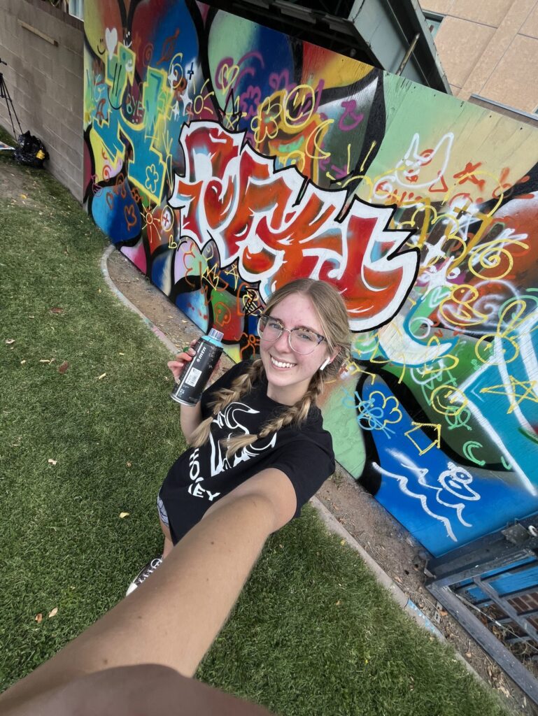Selfie of Ashley standing in front of finished mural
