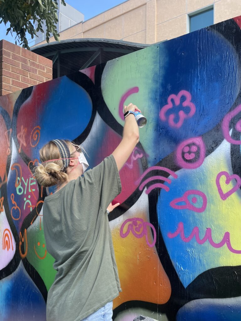 Ashley using spray paint to practice a doodle grid