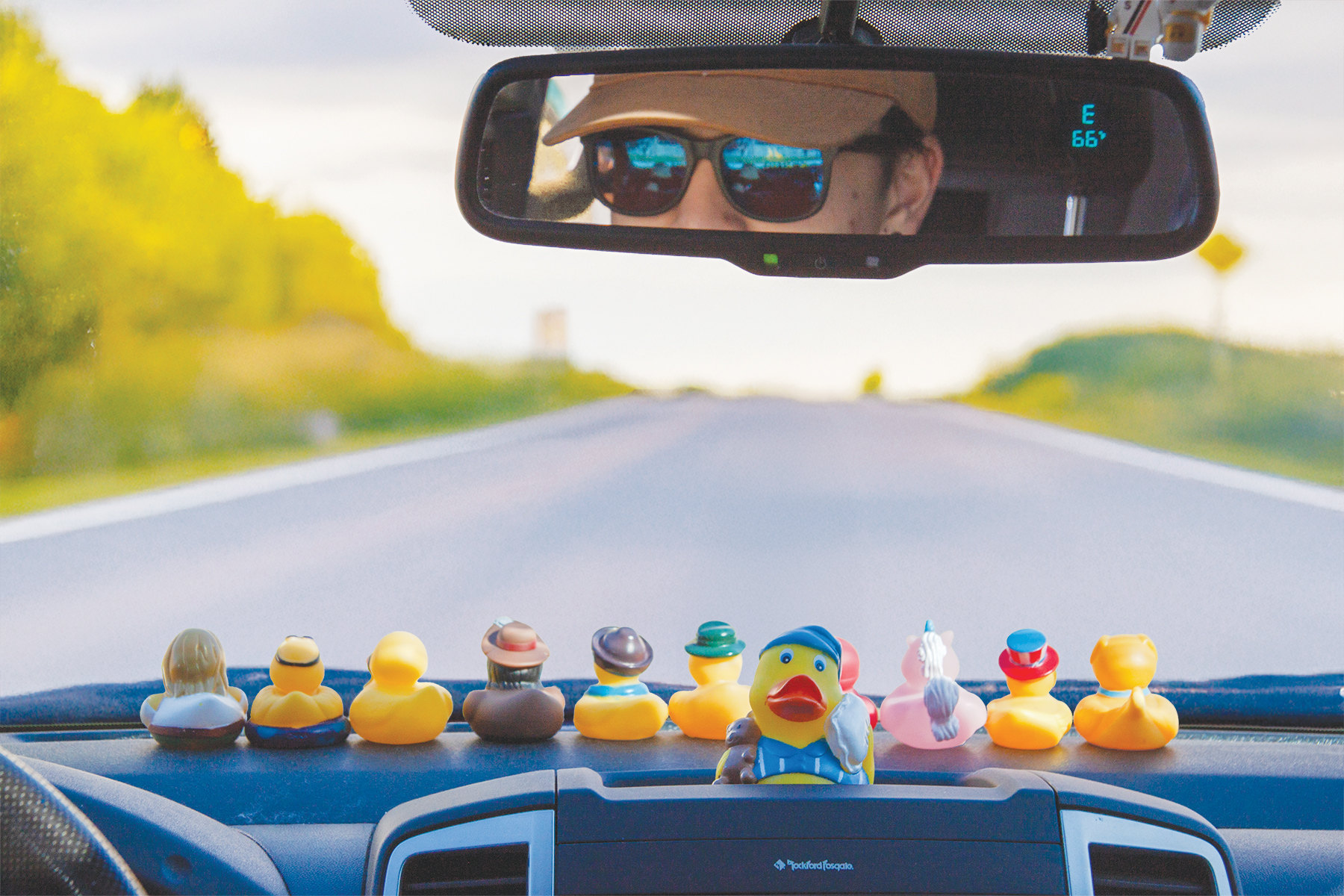 After edits. Dashboard of a car with rubber ducks on it, road ahead.