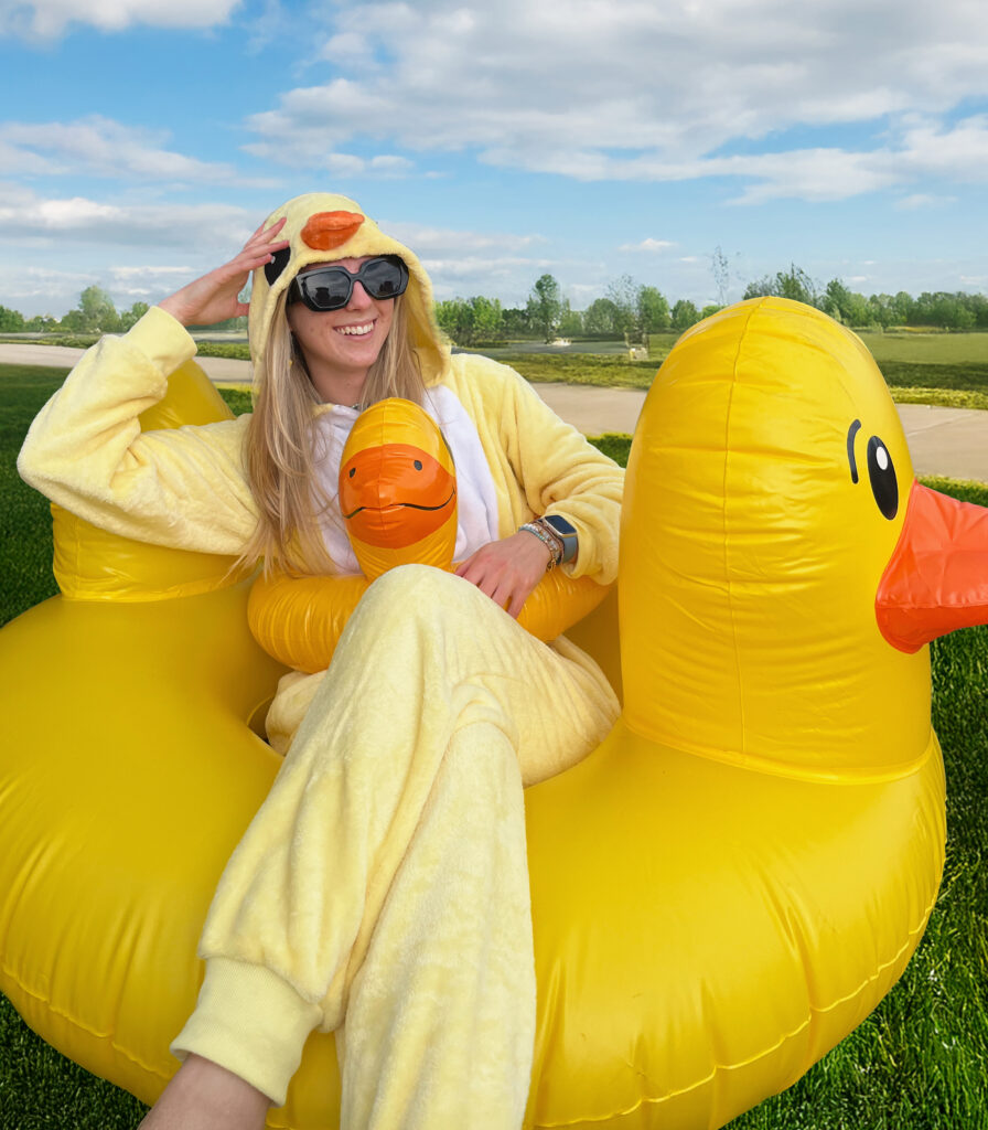 Ashley wearing a duck onesie and a mini duck floatie inside of a huge duck floatie.