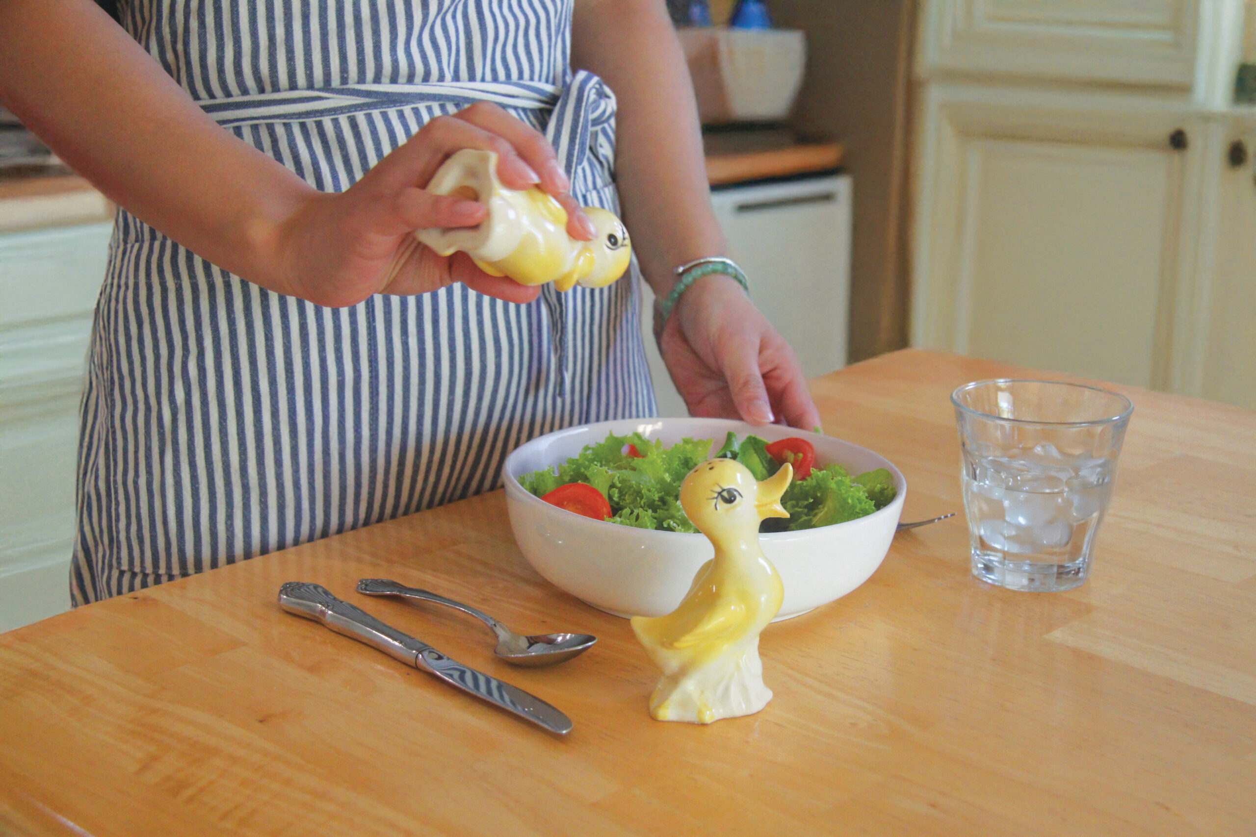 After edits. Shaking duck salt shaker into salad in a kitchen.